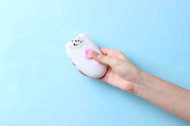 Modern Epilatör renkli bir arka plan üzerinde bir kadın elinde. İstenmeyen tüylerden kaldırma.