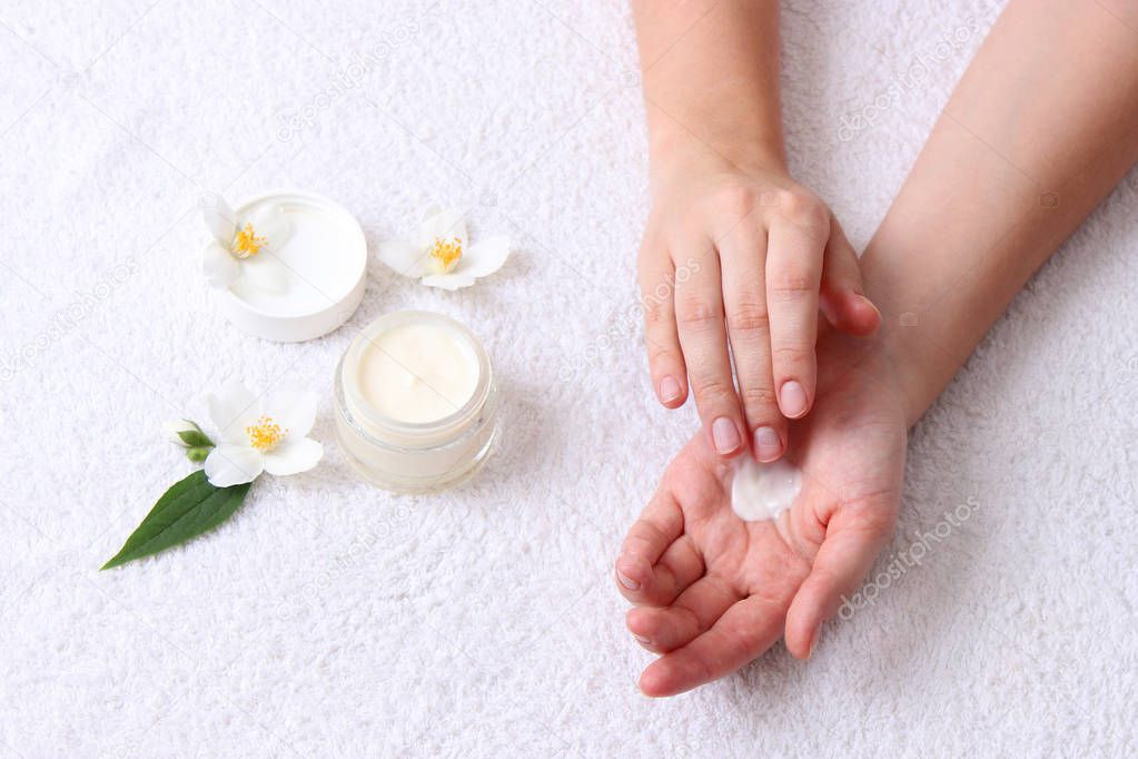 girl smears her hands cosmetic cream on the background of a towel. skin care, elastic and young skin of the hands.top view. 