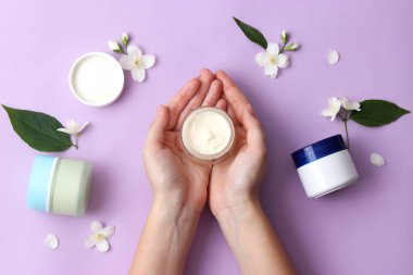 krem ve kadın elleri pastel bir arka plan üzerinde. çiçek, bir bakım kremleri ve eller bileşimi. minimalizm. Anti-Aging Krem. Cilt Bakımı. duygusuzca