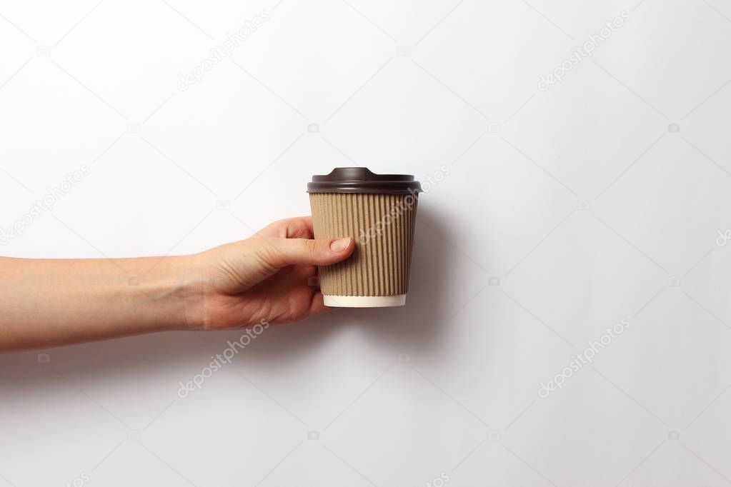 coffee in a cardboard glass in hand on a light background. minimalism, hot drinks.