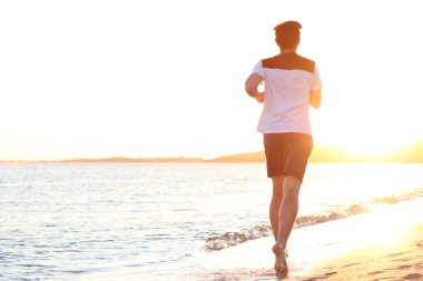 gün batımına karşı sahil boyunca adam çalışır