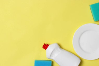 Bulaşık yıkama yardımcıları, Süngerler ve renkli bir arka planda bir plaka, üst görünüm. Ev işi, yemekleri yıka. flatlay