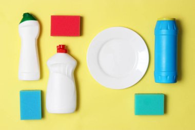Bulaşık yıkama yardımcıları, Süngerler ve renkli bir arka planda bir plaka, üst görünüm. Ev işi, yemekleri yıka. flatlay
