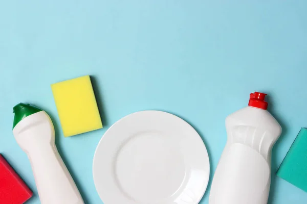 dish washing aids, sponges and a plate on a colored background, top view. Housework, wash the dishes.flatlay