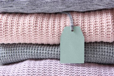 Hafif bir arka planda, ahşap bir masada bir yığın sıcak süveter. Sonbahar ve kış giysileri.