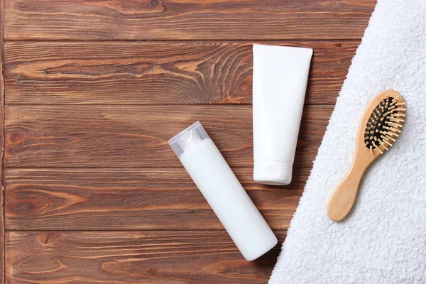 natural hair care products, hairbrush, towel and leaves on a wooden background top view. Shampoo, mask, balm. flatlay