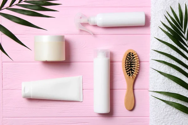 natural hair care products, hairbrush, towel and leaves on a wooden background top view. Shampoo, mask, balm. flatlay