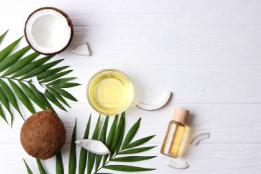 Hindistan cevizi ve hindistan cevizi yağı ve ahşap arka planda tropikal yapraklar.