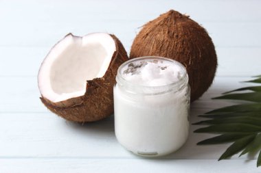 Hindistan cevizi ve hindistan cevizi yağı ve ahşap arka planda tropikal yapraklar.