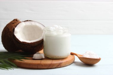 Hindistan cevizi ve hindistan cevizi yağı ve ahşap arka planda tropikal yapraklar.