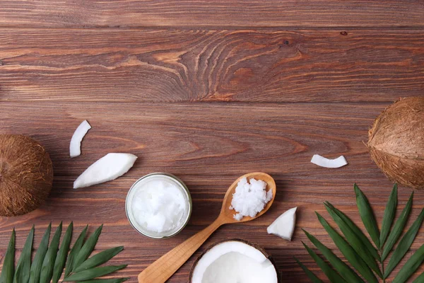 Kokosnüsse Und Kokosöl Mit Tropischen Blättern Auf Holzgrund — Stockfoto