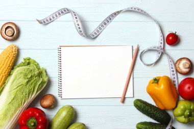 Taze sebzeler, mezura ve tahta masadaki kağıt not defteri. Üst Manzara. Diyet planı, düzgün beslenme, kilo kaybı, sağlıklı beslenme. düz yat