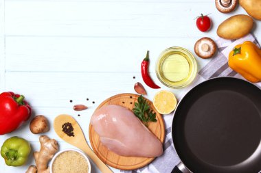Taze sebzeler, tavuk filetosu, baharatlar ve ahşap bir masada kızartma tavası. Üst manzara. Sağlıklı yemek, diyet, yemek. Yapışmayan kızartma tavası. düz yat