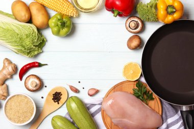 Taze sebzeler, tavuk filetosu, baharatlar ve ahşap bir masada kızartma tavası. Üst manzara. Sağlıklı yemek, diyet, yemek. Yapışmayan kızartma tavası. düz yat