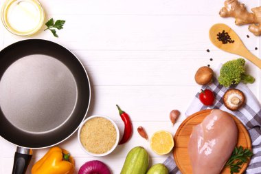 Taze sebzeler, tavuk filetosu, baharatlar ve ahşap bir masada kızartma tavası. Üst manzara. Sağlıklı yemek, diyet, yemek. Yapışmayan kızartma tavası. düz yat