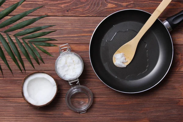 Frying pan and coconut oil on a wooden table. Top view. fry in coconut oil.