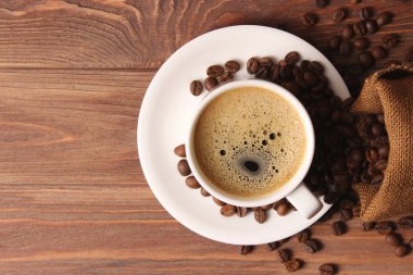 Ahşap arka planda bir fincan aromatik kahve ve kahve çekirdeği. Üst Manzara. Kahve.