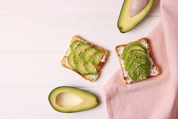 Toasted toast with avocado on a wooden table.