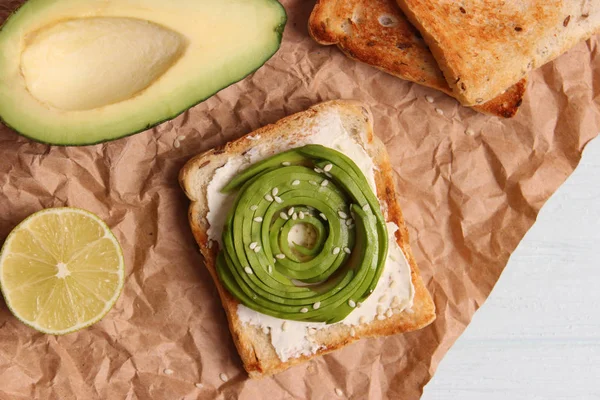 Toasted toast with avocado on a wooden table.