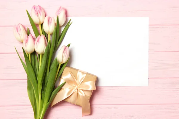 stock image A bouquet of beautiful tulips and a gift on a wooden background top view. Mother's Day Background, International Women's Day. Holiday, give a gift.