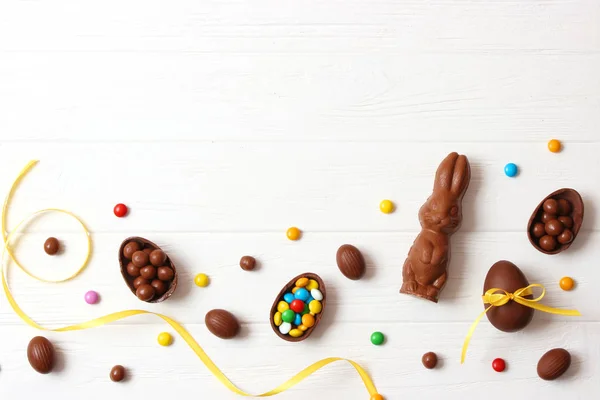 Easter composition with chocolate eggs and chocolate rabbit on wooden background, place for text