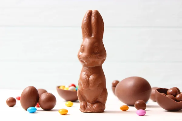 Easter composition with chocolate eggs and chocolate rabbit on wooden background, place for text