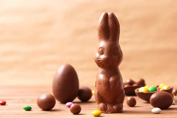 Easter composition with chocolate eggs and chocolate rabbit on wooden background, place for text