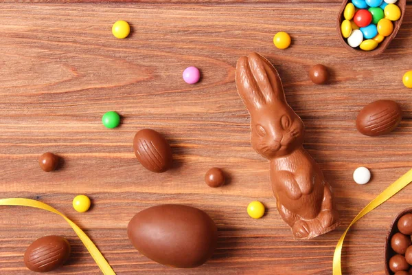 Easter composition with chocolate eggs and chocolate rabbit on wooden background, place for text