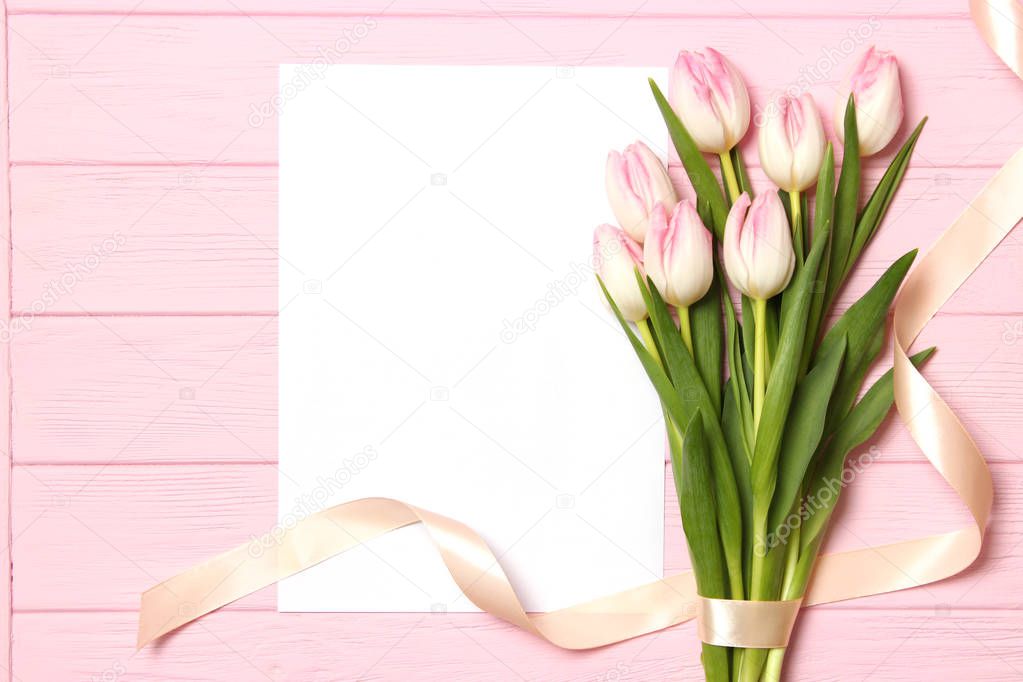 A bouquet of beautiful tulips and a card for text on a wooden background fork on top. Mother's day background, International Women's Day, birthday. Holiday, give.