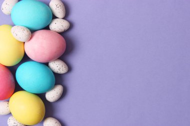 Paskalya bileşimi boyalı yumurta ve renkli bir arka plan tüyler. Paskalya arka plan
