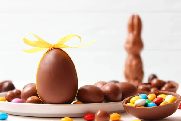 Easter composition with chocolate eggs and chocolate rabbit on wooden background, place for text