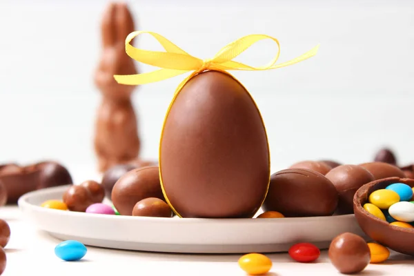 Easter composition with chocolate eggs and chocolate rabbit on wooden background, place for text