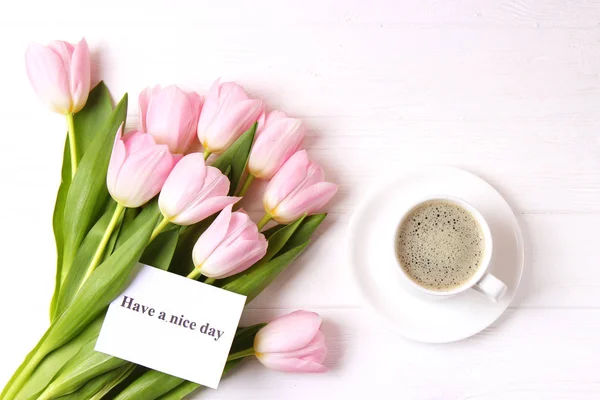 Cup of coffee, a bouquet of flowers and a card with the inscription \