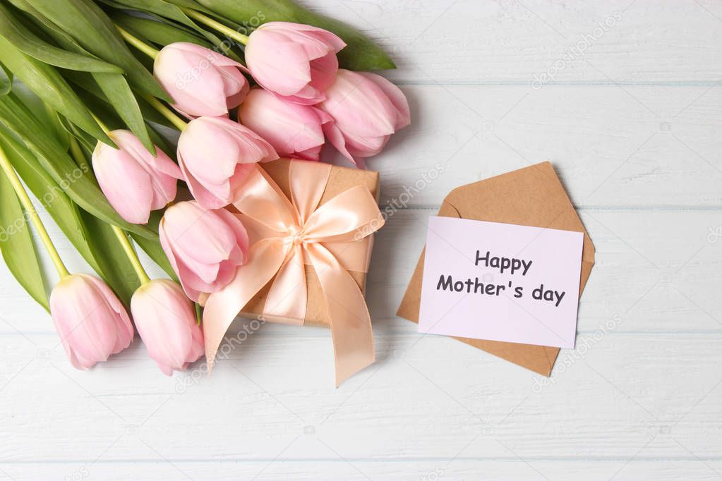 Beautiful composition for the Day of Mother on wooden background top view. Flowers, greeting card, gift.