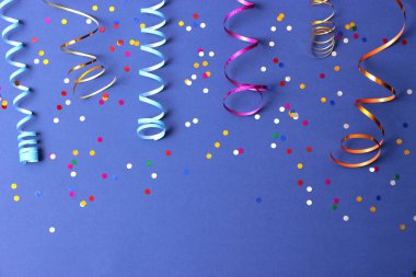 Festive background of ribbons and confetti on a colored background top view. clipart