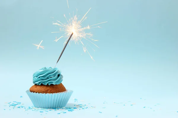 cupcake with sparkler on a colored background. Background for the holiday, birthday