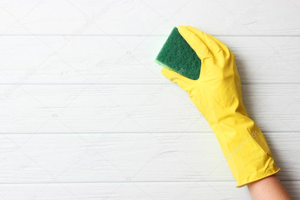 female hand in cleaning glove and rag on colored background