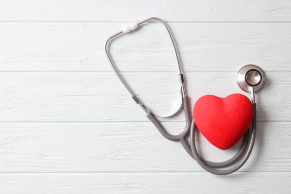 木製の色の背景に聴診器と心臓 — ストック写真
