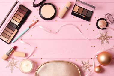 Renkli bir arka planda profesyonel dekoratif kozmetik seti ve Noel aksesuarları.