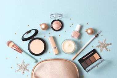 Renkli bir arka planda profesyonel dekoratif kozmetik seti ve Noel aksesuarları.