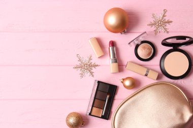 Renkli bir arka planda profesyonel dekoratif kozmetik seti ve Noel aksesuarları.