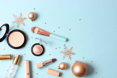 Renkli bir arka planda profesyonel dekoratif kozmetik seti ve Noel aksesuarları.