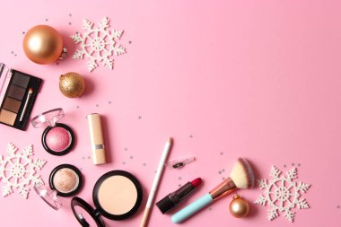 Renkli bir arka planda profesyonel dekoratif kozmetik seti ve Noel aksesuarları.