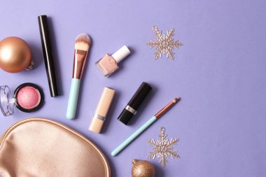 Renkli bir arka planda profesyonel dekoratif kozmetik seti ve Noel aksesuarları.