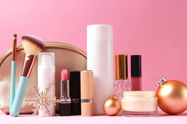 Renkli bir arka planda profesyonel dekoratif kozmetik seti ve Noel aksesuarları.