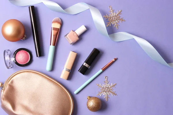 Renkli bir arka planda profesyonel dekoratif kozmetik seti ve Noel aksesuarları.