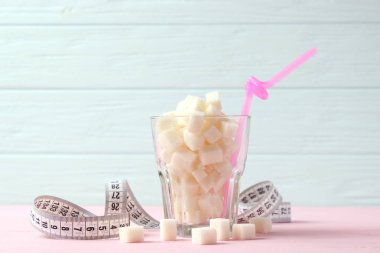 Bardaktaki şeker ve renkli bir arka planda mezura. Kilo kontrolü, sağlıklı yemek, diyet..