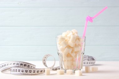 Bardaktaki şeker ve renkli bir arka planda mezura. Kilo kontrolü, sağlıklı yemek, diyet..