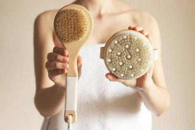 Kız evde doğal kıllı masaj fırçası kullanıyor. Selülit önleme, cilt bakımı