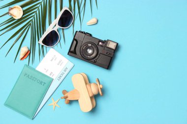 renkli arkaplan görünümünde seyahat aksesuarları ve tropikal yapraklar.